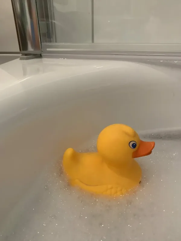 Persönliche Assistenz kann auch bei sehr intimen Dingen wie der Hygiene und Pflege nach Anleitung unterstützen. Auf dem Foto zu sehen eine Badewanne mit Schaumbad und einem Quietsche-Entchen in Gelb.
