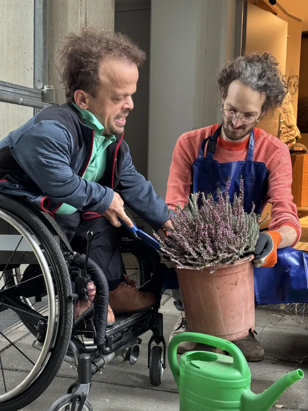 Persönliche Assistenz unterstützt beim Umtopfen von Blumen am Balkon.