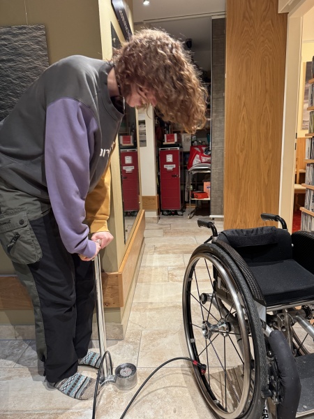 Unterstützung im Haushalt, hier beim Keller einräumen Persönliche Assistentin Anna hilft bei der Wartung vom Rollstuhl und pumpt die Reifen auf 7 bar auf.